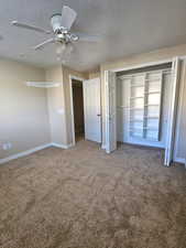 Unfurnished bedroom with a textured ceiling, a closet, carpet, and a ceiling fan