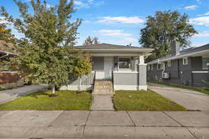View of front of property with a front yard, a porch, and brick siding