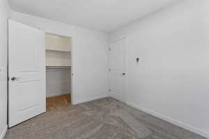 Unfurnished bedroom featuring light colored carpet and a spacious closet