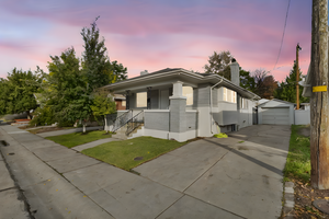 View of front of house with a chimney, an outdoor structure, concrete driveway, a detached garage, and covered porch