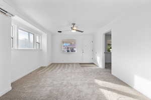 Unfurnished room featuring crown molding, plenty of natural light, an AC wall unit, light colored carpet, and a ceiling fan