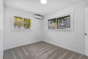 Unfurnished room featuring carpet and an AC wall unit