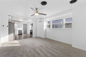 Unfurnished living room featuring dark carpet, crown molding, a ceiling fan, and a wall unit AC