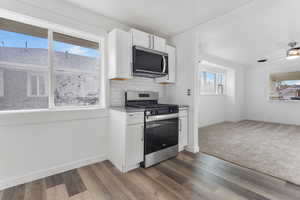 Kitchen featuring white cabinetry, appliances with stainless steel finishes, backsplash, and dark wood-style floors