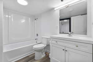Full bath featuring a textured ceiling, vanity, dark wood-type flooring, and shower / washtub combination