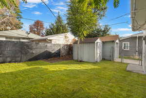 Fenced backyard with a storage unit and a gate