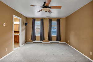 Primary bedroom with light carpet, a textured ceiling, ceiling fan, and a baseboard radiator