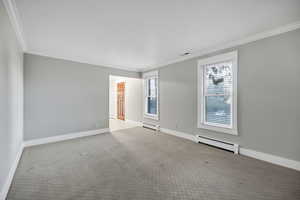 Formal living room with crown molding, carpet floors, baseboard heating, and a baseboard heating unit