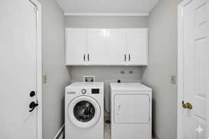 Virtually Staged Laundry room with cabinet space, baseboard heating, and washing machine and dryer