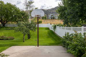 Fenced backyard with a basketball court and a mountain view