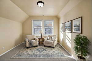 Virtually staged - Living area with carpet, a textured ceiling, vaulted ceiling, and a baseboard heating unit