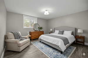 Virtually Staged Downstairs Bedroom with wood finished floors and baseboards