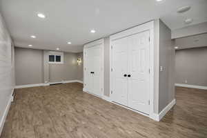 Finished below grade area with recessed lighting, wood finished floors, and a baseboard radiator