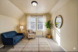 Virtually staged - Sitting room featuring carpet, a textured ceiling, vaulted ceiling, and a baseboard heating unit