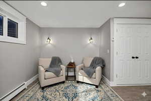 virtually staged - Living area featuring a baseboard heating unit, wood finished floors, and recessed lighting