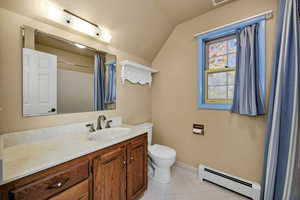 Full bathroom upstairs featuring baseboard heating, vanity, light tile patterned floors, curtained shower, and lofted ceiling