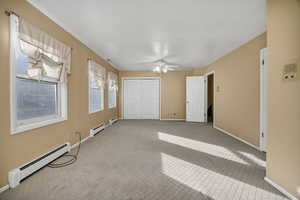 Unfurnished upstairs bedroom with a baseboard heating unit, carpet, a closet, and a ceiling fan