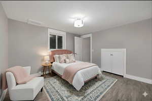 Virtually Staged Downstairs Bedroom featuring wood finished floors and baseboard heating
