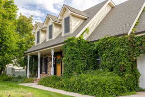 New england style home with roof with shingles, a porch, brick siding, a front lawn, and a garage