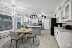 Virtually Staged Kitchen featuring white cabinets, ornamental molding, light countertops, decorative light fixtures, and appliances with stainless steel finishes