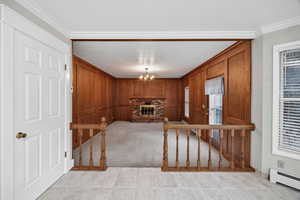 Family room with crown molding, a brick fireplace, baseboard heating, and light colored carpet