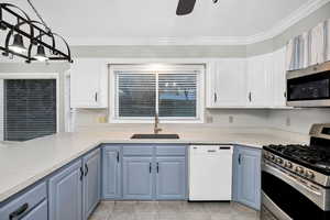 Kitchen featuring appliances with stainless steel finishes, blue cabinetry, white cabinets, ornamental molding, and light countertops
