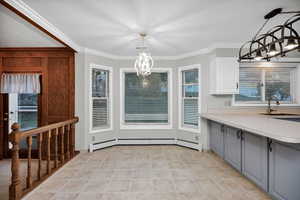 Unfurnished dining area with a chandelier, crown molding, a baseboard radiator, and light tile patterned floors