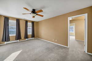Primary bedroom featuring carpet, baseboard heating, and a ceiling fan