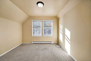 Upstairs bedroom featuring carpet flooring, a textured ceiling, a baseboard heating unit, and vaulted ceiling