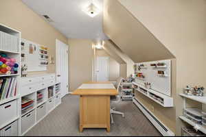 Virtually Staged bedroom, craft room or Office area with baseboard heating, a textured ceiling, dark colored carpet, and lofted ceiling