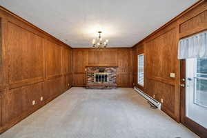 Family room featuring wood walls, a brick fireplace, a baseboard heating unit, light carpet, and crown molding