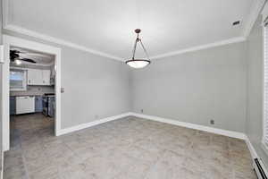 Formal dining area featuring crown molding, baseboard heating, a ceiling fan, and light tile patterned flooring