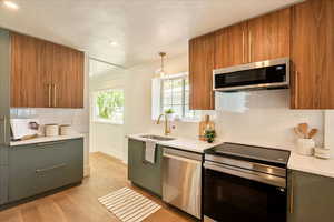 Kitchen with stainless steel appliances, decorative backsplash, light wood-type flooring, modern cabinets, and recessed lighting