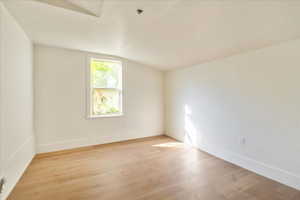 Unfurnished room featuring light wood-type flooring and vaulted ceiling