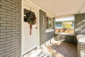 Property entrance with a porch and brick siding
