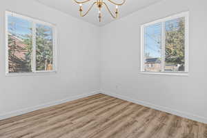 Spare room featuring a chandelier and wood finished floors