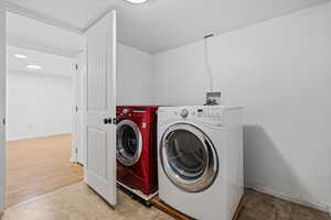 Laundry area with washer and clothes dryer and tile patterned floors