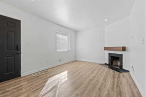 Unfurnished living room with light wood finished floors, recessed lighting, and a tile fireplace