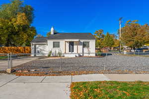 View of front of home featuring concrete driveway, an attached garage, a chimney, brick siding, and a fenced front yard