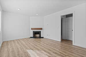 Unfurnished living room featuring recessed lighting, light wood-type flooring, and a tiled fireplace