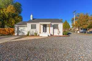 View of front of property featuring an attached garage, driveway, a chimney, a shingled roof, and brick siding