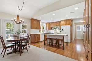 Dining space with light wood-type flooring, lofted ceiling, a chandelier, and recessed lighting