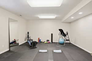 Workout room featuring dark rubber floors, a textured ceiling, and recessed lighting