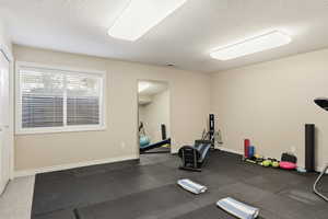 Workout area featuring a textured ceiling and dark rubber floors