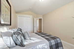 Carpeted bedroom with vaulted ceiling and a closet