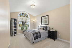 Bedroom featuring light carpet and vaulted ceiling