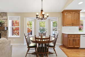 Dining area with light carpet, a chandelier, recessed lighting, and a fireplace