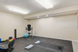 Exercise area featuring a textured ceiling, dark flooring, and recessed lighting