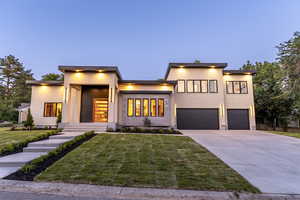 Contemporary home featuring stucco siding, driveway, a front yard, and an attached garage