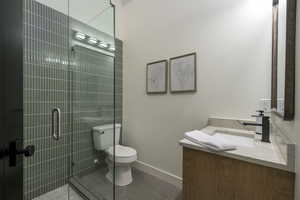 Full bath with vanity, dark tile patterned flooring, and a stall shower